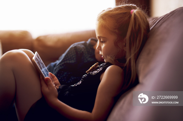 Little girl watching cartoons on tablet.