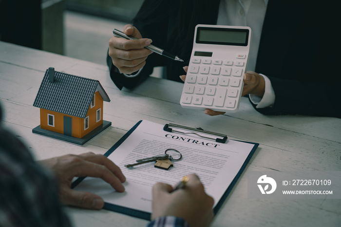 Real estate professionals offer their clients contracts to discuss home purchases, insurance or real estate loans. Home sales agents sit at the office with new home buyers in the office.