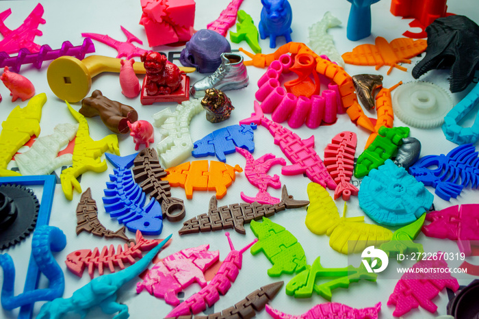 Many bright multi-colored objects printed on 3d printer lie on flat surface close-up. Fused deposition modeling, FDM. Concept modern progressive additive technology for 3d printing.