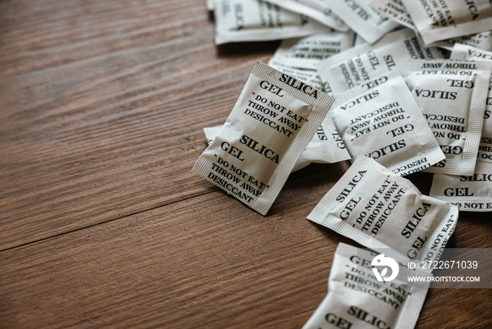 Desiccant or silica gel in white paper packaging on a wooden background.