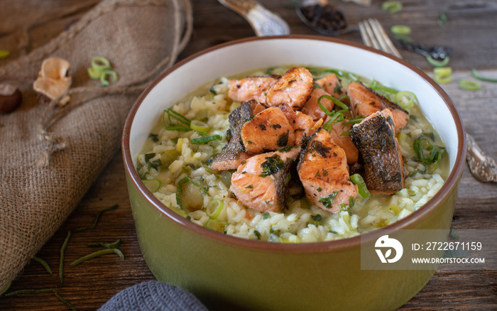 Fried salmon fillet with leek, parmesan cheese risotto served on wooden table