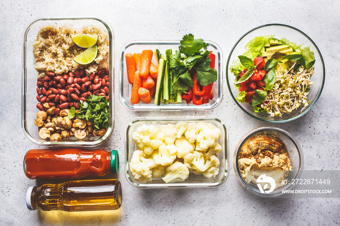 Healthy vegan food in glass containers, top view. Rice, beans, vegetables, hummus and juice.