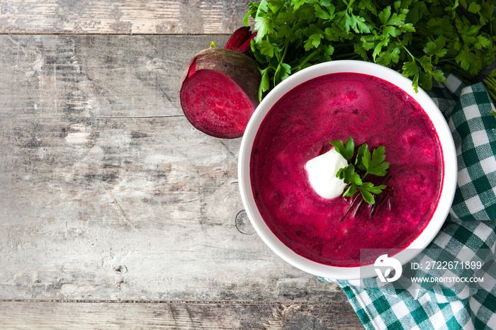 Beet soup in white bowl on wooden table