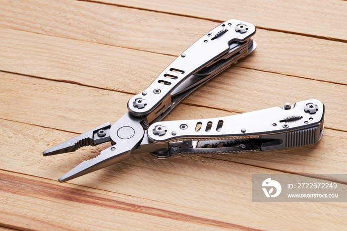 stainless steel multitool pocket knife. tourist survival tool over wooden desk background