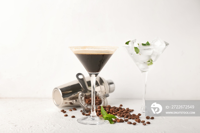 Glass of tasty espresso martini cocktail and shacker on light background