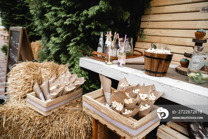 Wedding banquet decorations. Wood rustic style decor. Festive table with desserts, snacks, cakes, blackberry and popcorn. Receptions Tarlets. Decorations made of wood with flowers and greenery.