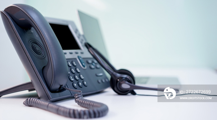 close up soft focus on headset with telephone devices at office desk for customer service support concept