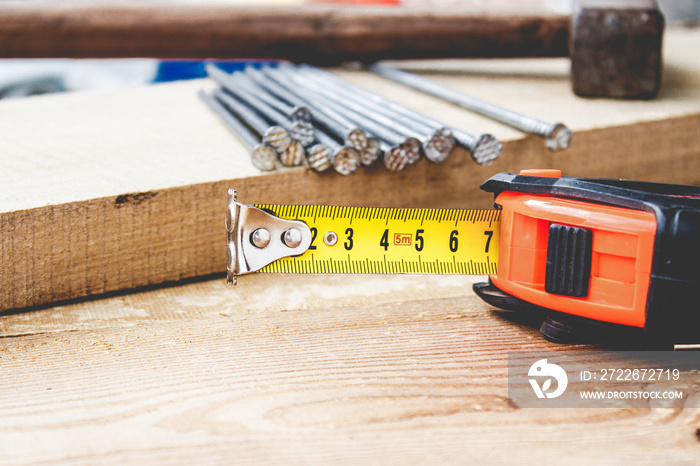 Old hammer with nails and a yellow ruler of roulette on a blackboard background. Tools for construction work.