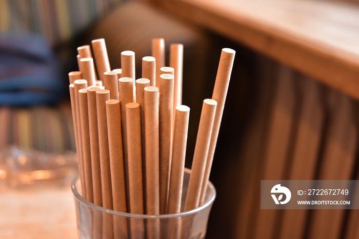 Eco friendly Reusable Straws in the cardboard cup with selective focus and blurred ba. Paper cocktail tubes. Kraft paper straw for drinking coffee or tea. Disposable cocktail tube.