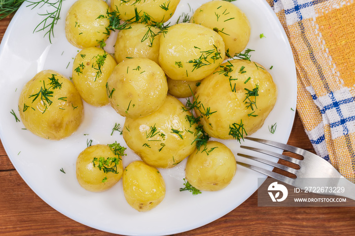 Top view of boiled young potatoes with dill on dish