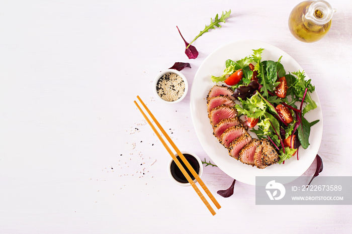 Japanese traditional salad with pieces of medium-rare grilled Ahi tuna and sesame with fresh vegetable salad on a plate. Authentic Japanese food. Top view. Copy space.