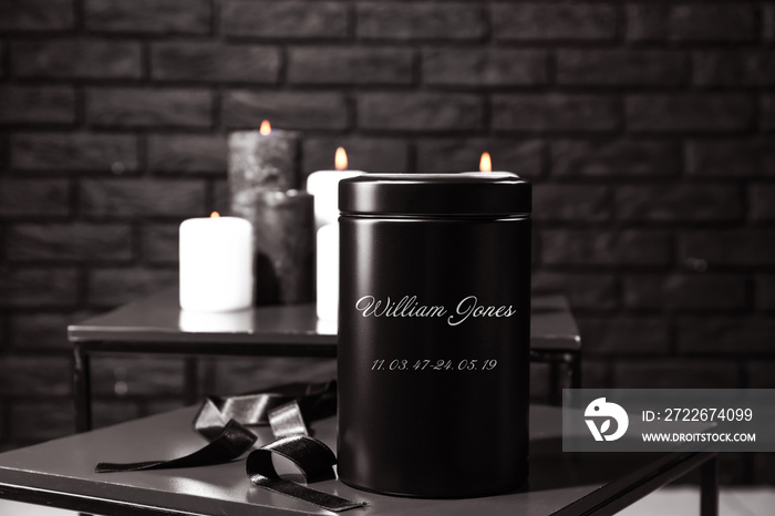 Mortuary urn with ribbon on table in room