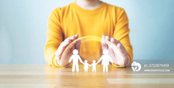 Hand protecting family on wood table. Healthcare and life insurance concept