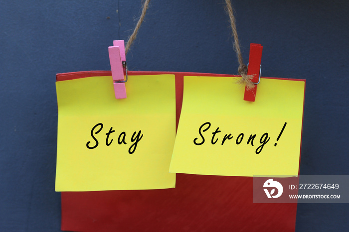 Inspirational quote - Stay strong. With origami paper notes hanging on wall. Encouragement concept with colorful creative papers.