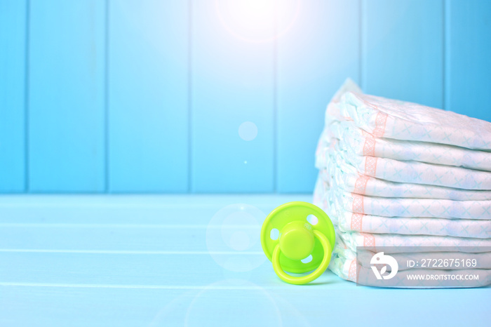 Baby accessories background. Pile of diapers with dummy. Copy space.