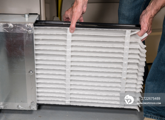 Senior man inserting a new air filter in a HVAC Furnace