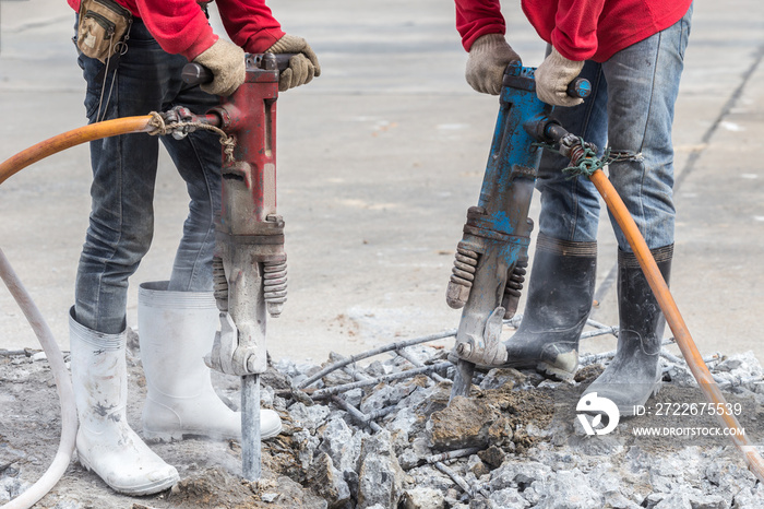 Construction worker removes excess concrete with drilling machin