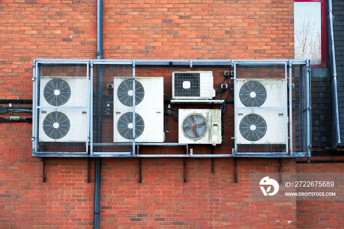 Air Conditioning condensers in cage hanging on wall