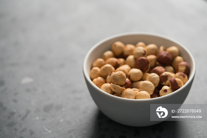 roasted hazelnuts in white bowl on concrete background