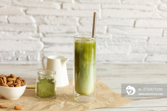 Green tea matcha iced latte with almond milk on light background.