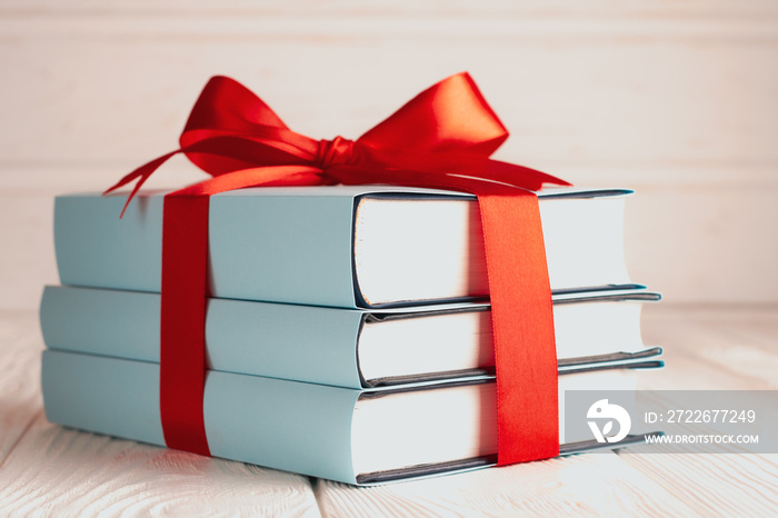 Close up of books tied with ribbon on wooden background: concept of donating books