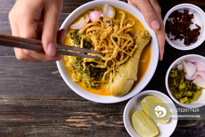 Northern Thai food (Khao Soi), Spicy curry noodles soup with chicken on wooden background, Local Thai food