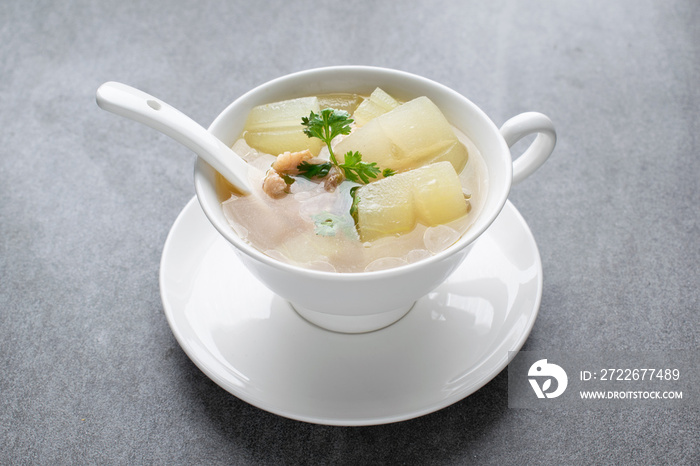 Boiled winter melon soup with chicken rib in white bowl on table.