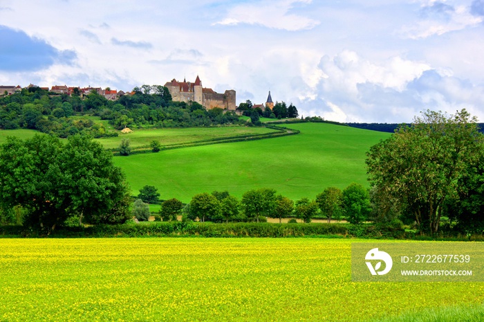 Castle and village of Chateauneuf en Auxois behind rolling green hills, Burgundy, France