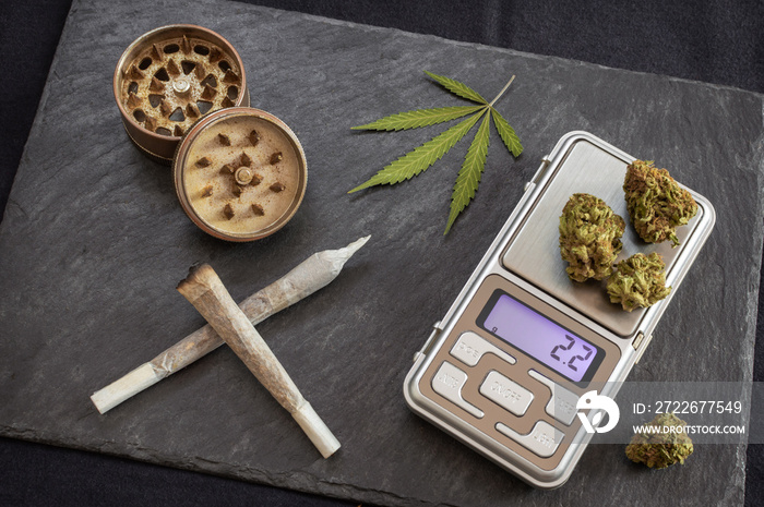 Marijuana joints ready to smoke and digital scale for weighing the dose. High quality cannabis, grinder and marijuana leaf in a gourmet coffeeshop.