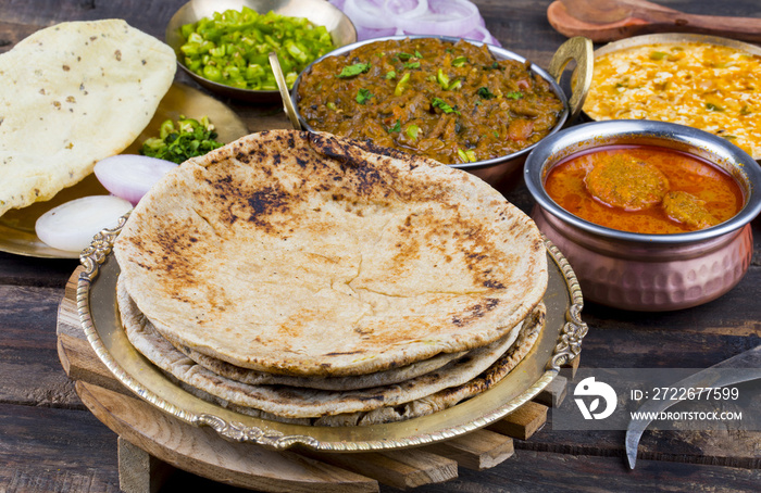 Indian Cuisine Chapati Also Called Roti, Flatbread, Chapathi or Chapatti Served With Sev Tamatar, Gatta Curry, Raita, Papad or Onion on Wooden Background