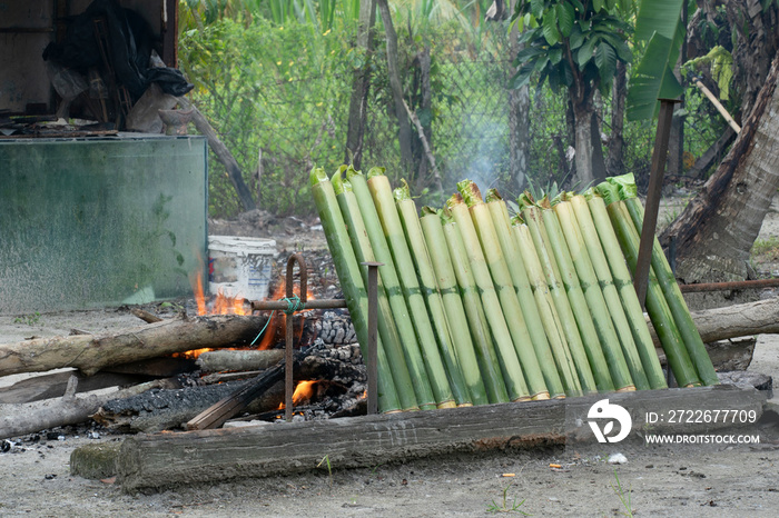 A row of lemang at the beginning of the cooking process. Lemang is a staple traditional malay food during eid festival. Blurred background