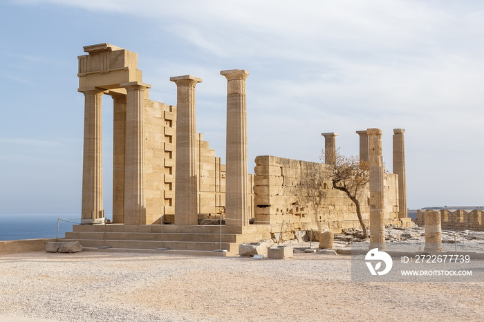 Ancient Greek acropolis. Front view of columns and walls. near the tree grows.