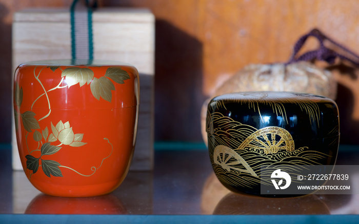 Japanese black lacquer tea caddy with gold Genji Guruma makie design, and red lacquer tea caddy with auspicious gold makie chrysanthemum design, used in the Japanese Tea Ceremony.