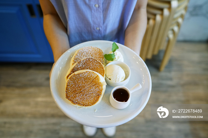 Homemade fluffy souffle pancakes, topped with icing, served with maple syrup, whipped cream and vanilla ice cream.