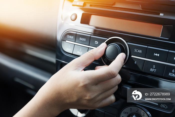 Woman turning button of radio in car