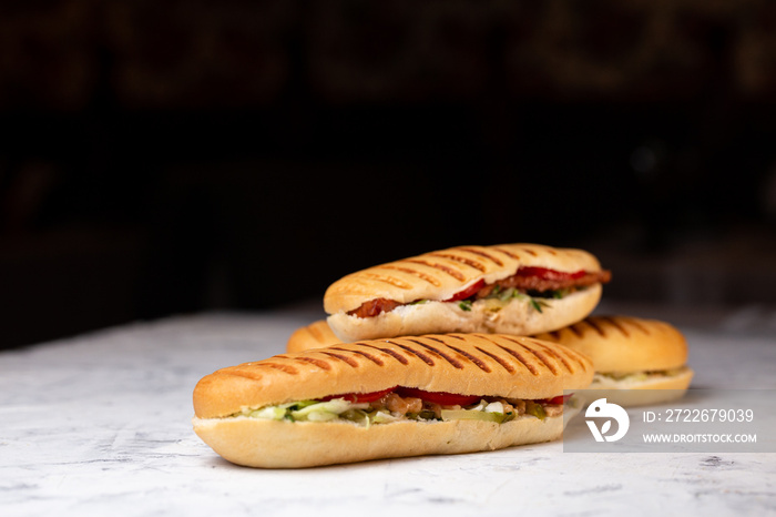 three panini stuffed on a dark background