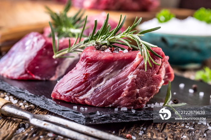 Raw beef meat. Raw beef tenderloin steak on a cutting board with rosemary pepper salt in other positions.