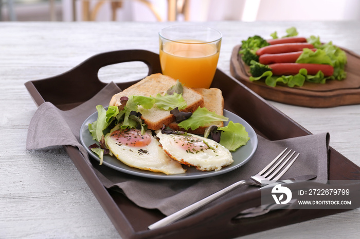 Composition with homemade tasty breakfast with fried eggs on wooden tray