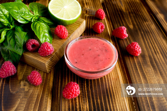 Salad sauce  with  raspberries and basil on the brown wooden background