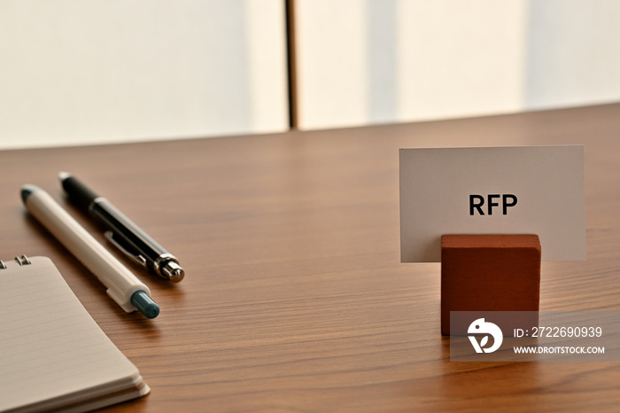 There is a card on paper stand with the word of RFP which is an abbreviation for Request For Information on the desk with a pen.