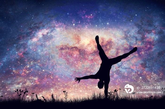 Happy man doing cartwheel on night sky with nebula and stars