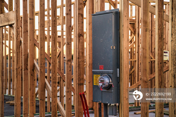 Main electrical panelboard (electric panel) and meter for residential new construction home installed on the stud frame of house