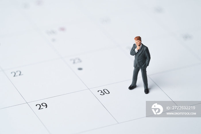 Businessman miniature figure standing on number date 30 on calendar for getting money of pay day of salary concept.