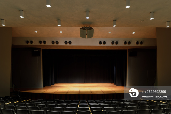 Empty Stage Auditorium with Lit Stage and Black Curtain