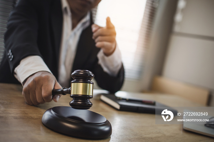 justice lawyer in black suit pointing finger and knocking wooden judge gavel with documents on workplace desk in courtroom office, occupation, business, justice law and legal service concept