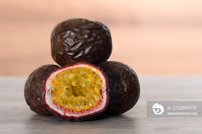 Purple maracuya,passion fruit on a wooden board, front view for background or wallpaper. Fresh fruit cut in half, used in desserts, sweet and sour.