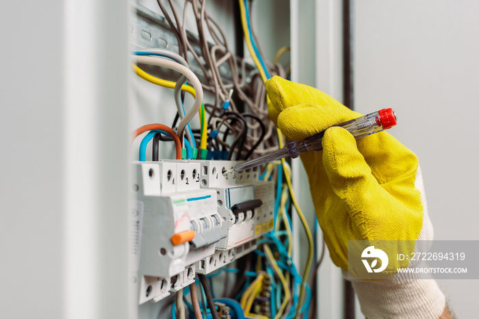 Selective focus of electrician using screwdriver while fixing electric panel