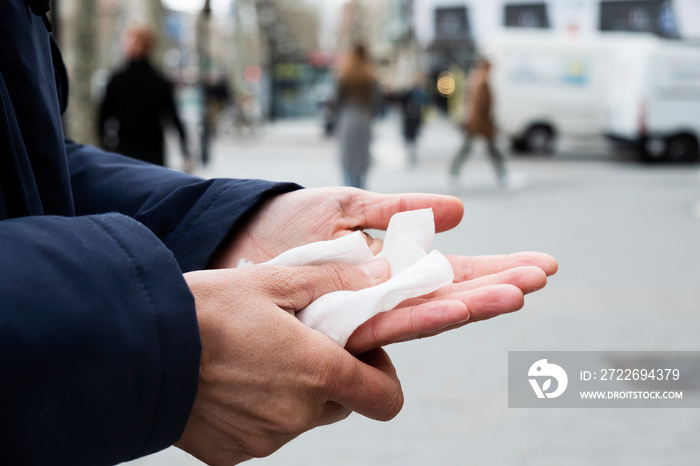 man disinfecting his hands with a wet wipe