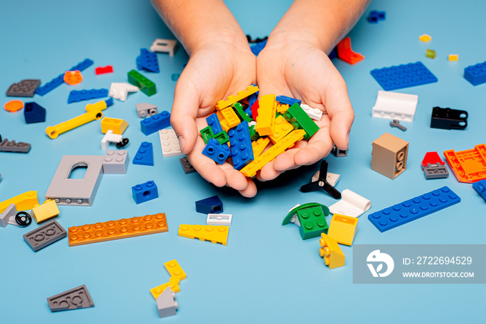 Close up of child’s hands playing with colorful plastic bricks at the table