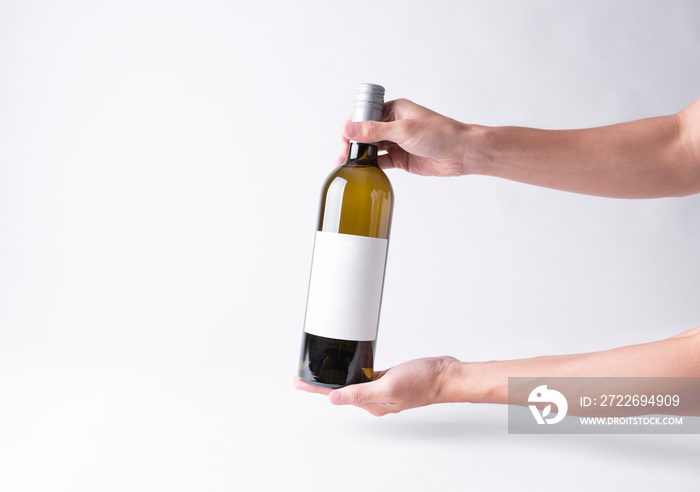 Hand holding a wine bottle for mock-up. Blank Label on a gray background.